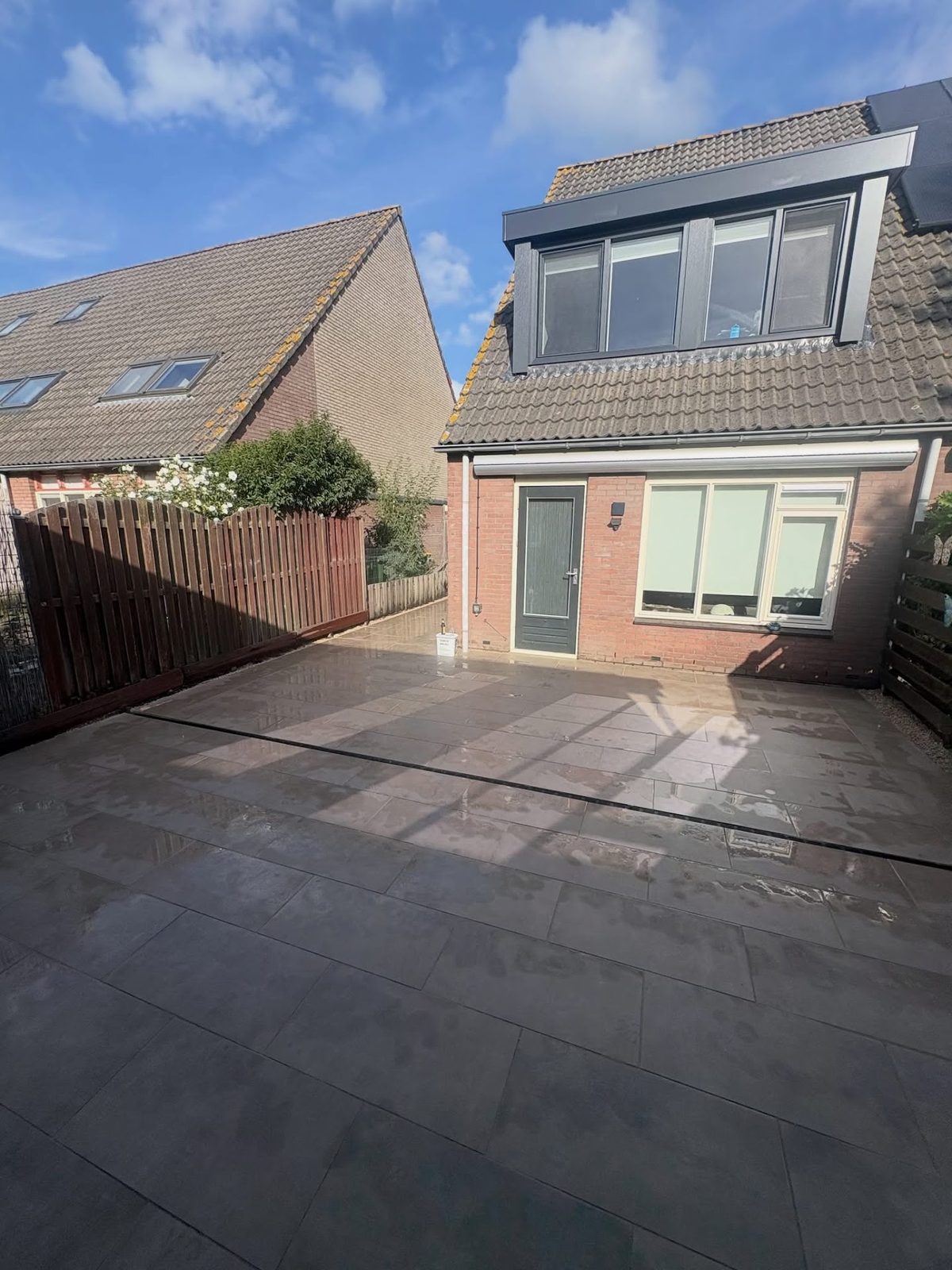 Nieuw bestraat terras met grote keramische tegels in de achtertuin in Ede
